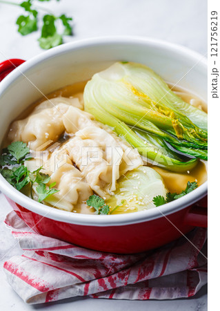 Gyoza soup with mushroom broth and bok choy in red saucepan. Asian cuisine concept. Gyoza soup with mushroom broth and bok choy in red saucepan. Asian cuisine concept. 121756219