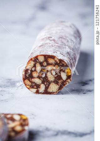 Chocolate salami with nuts on white background. Traditional Italian sweet sausage for Easter. Chocolate salami with nuts on white background. Traditional Italian sweet sausage for Easter. 121756241