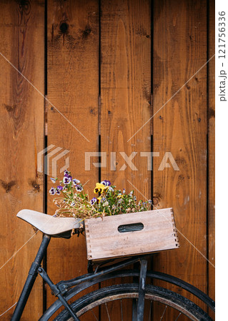 Vintage bicycle with wooden crate filled with flowers against rustic wooden wall, showcasing eco-friendly urban gardening and sustainable decor Vintage bicycle with wooden crate filled with flowers against rustic wooden wall, showcasing eco-friendly urban gardening and sustainable decor 121756336
