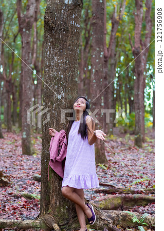 beautiful young asian woman hiding from tropical rain under a tree 121756908