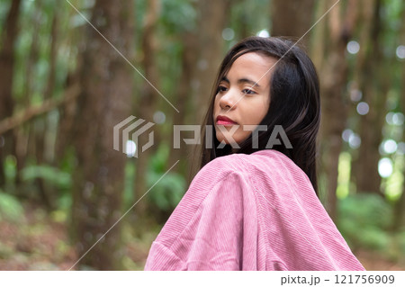 young filipino woman in the forest wearing a pink cape with a hood, walking outdoors 121756909