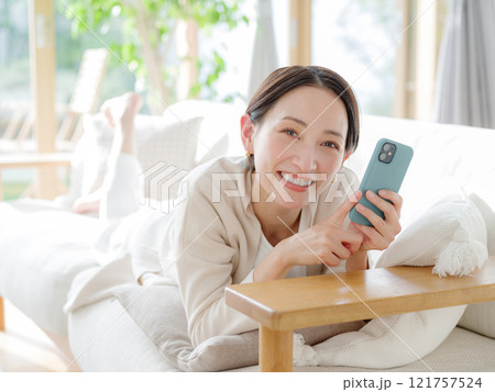 ソファでスマートフォンを持つ女性 ソファでスマートフォンを持つ女性 121757524