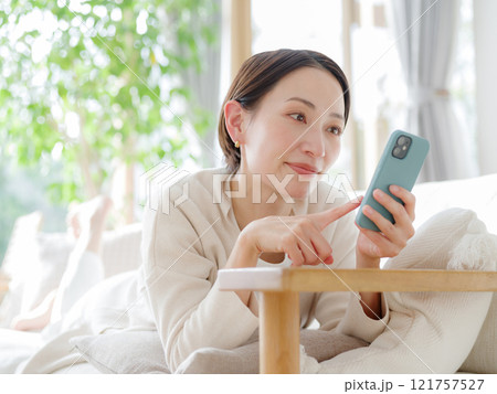 ソファでスマートフォンを持つ女性 121757527