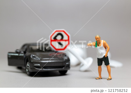 A Drunk driver holding a liquor bottle as he steps out of a car. concepts of reckless behavior, urban life 121758252