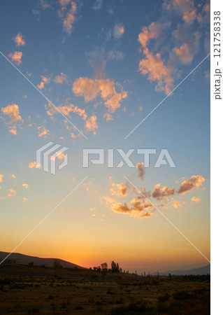 small clouds painted in sunset colors on blue sky 121758338