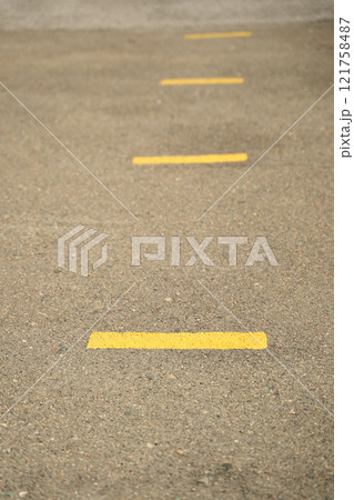 Close up view of yellow road lines on asphalt pavement for traffic safety Close up view of yellow road lines on asphalt pavement for traffic safety 121758487