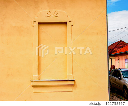 Decorative window on an old yellow plaster wall. 121758567