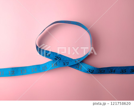 Top view blue measuring tape on a pink background. Medical and health concept. Top view blue measuring tape on a pink background. Medical and health concept. 121758620