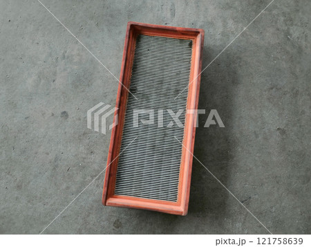 A car air filter placed on the floor of a workshop. 121758639