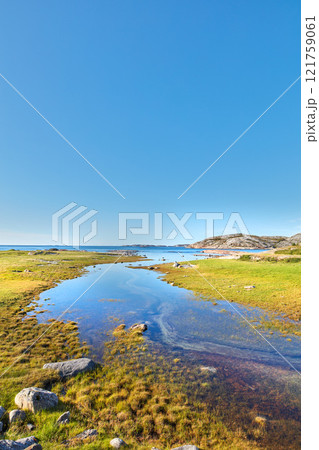 Scenic view of a river flowing through a swamp and leading to the ocean in Norway. Landscape view of blue copy space sky and a marshland. Overflow of water pollution and oil deposits entering the sea Scenic view of a river flowing through a swamp and leading to the ocean in Norway. Landscape view of blue copy space sky and a marshland. Overflow of water pollution and oil deposits entering the sea 121759061