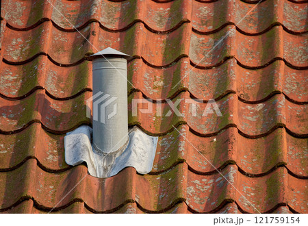 Air flow ventilation pillar and chimney on a slate roof of q house or factory building outside with copyspace. Construction of an exterior vent on rooftop for fireplace or oven smoke and heat control 121759154