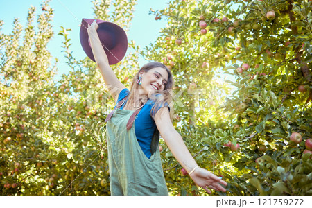 Excited young woman jumping for joy in an apple orchard on a sunny day outside. Happy and cheerful farmer feeling optimistic, free and full of energy after a fruitful harvest on her successful farm Excited young woman jumping for joy in an apple orchard on a sunny day outside. Happy and cheerful farmer feeling optimistic, free and full of energy after a fruitful harvest on her successful farm 121759272