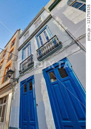 Classic architecture of vibrant buildings with blue doors in a city. Low angle of ancient and traditional homes or houses in a small vintage town or village with bright colors and a unique design Classic architecture of vibrant buildings with blue doors in a city. Low angle of ancient and traditional homes or houses in a small vintage town or village with bright colors and a unique design 121759326