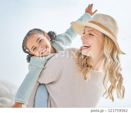 Portrait of a mother and daughter having fun and bonding on a beach vacation together. Happy adopted black child being playful and cute with her caucasian foster mom. Parent and kid enjoying summer Portrait of a mother and daughter having fun and bonding on a beach vacation together. Happy adopted black child being playful and cute with her caucasian foster mom. Parent and kid enjoying summer 121759562