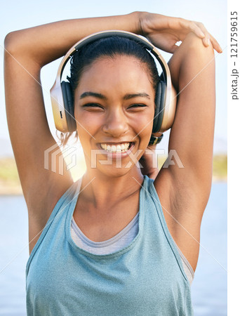 Portrait of happy woman doing warmup stretches, using headphones for music and exercising outside. Smiling female athlete preparing body and muscle for training or running cardio workout Portrait of happy woman doing warmup stretches, using headphones for music and exercising outside. Smiling female athlete preparing body and muscle for training or running cardio workout 121759615