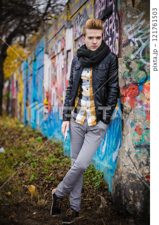 Fashion man holds mobile phone outdoor 121761503