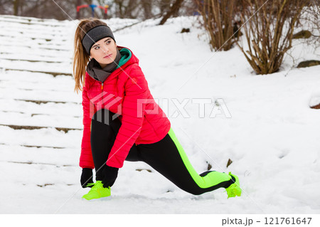 Woman wearing sportswear exercising outside during winter 121761647