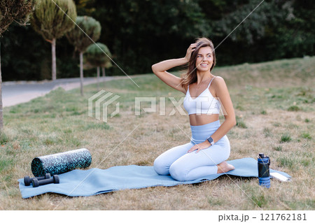 Young woman relaxing on yoga mat after exercising in the park 121762181