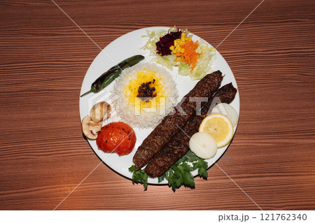 Turkish kebab plate with rice and salad on wooden background. Retro flash food photography Turkish kebab plate with rice and salad on wooden background. Retro flash food photography 121762340