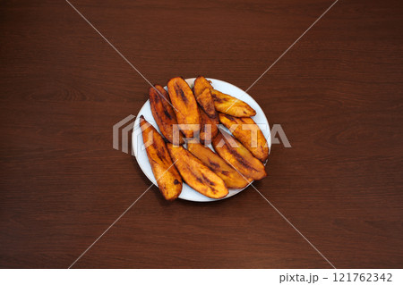 Fried plantain bananas on wooden background. Traditional African recipe cuisine 121762342