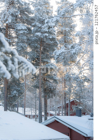 Winter forest in Finland, snow covered log cabin between the trees in Lapland, Finland Winter forest in Finland, snow covered log cabin between the trees in Lapland, Finland 121762457