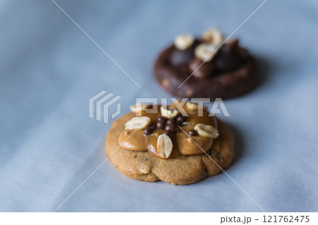 Close up of homemade american traditional chocolate chip cookie with peanut butter, caramel and peanuts topping. Dark chocolate cookie on the background. 121762475
