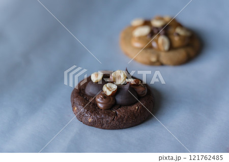 Homemade american dark chocolate cookie with chocolate cream and hazelnut topping with peanut butter cookie on background. Homemade american dark chocolate cookie with chocolate cream and hazelnut topping with peanut butter cookie on background. 121762485
