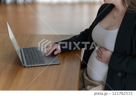 Cropped image of beautiful pregnant business woman using a laptop and holding one hand on her belly while working at home Cropped image of beautiful pregnant business woman using a laptop and holding one hand on her belly while working at home 121762515