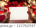 Woman hands holding a white blank valentine's day invitation mockup, Valentine's day scene in the background  121762597