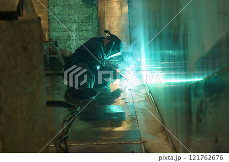 Welding sparks illuminate workshop as craftsman creates metal structure 121762676