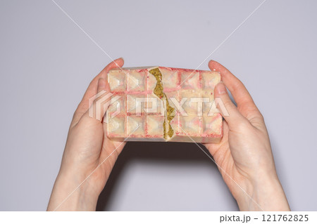 Popular white Dubai chocolate with pistachio, dried raspberry, tahini and kadaif filling, chocolate broken in woman's hands. Confectionery and handmade sweets, chocolatier Popular white Dubai chocolate with pistachio, dried raspberry, tahini and kadaif filling, chocolate broken in woman's hands. Confectionery and handmade sweets, chocolatier 121762825