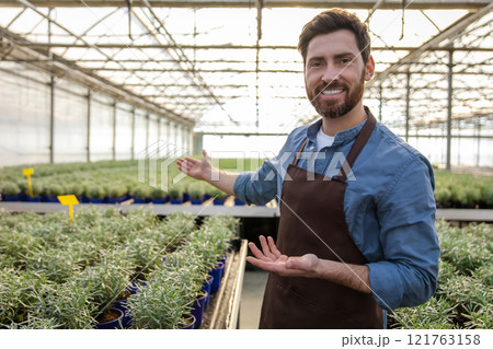 Positive bearded young man in a greenhouse looking determined 121763158