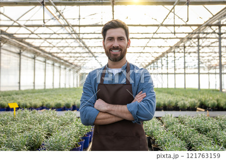 Positive bearded young man in a greenhouse looking determined 121763159