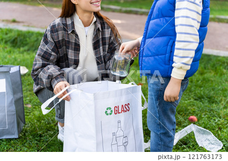 Woman volunteer and boy cleaning garbage together in social project 121763173