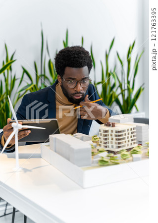 African american architect looking focused while scrutinizing the new mock up of a living building 121763395