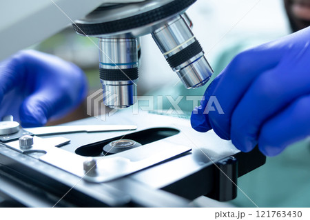Medical man working in lab using microscope for analysis of virus testing and vaccine 121763430