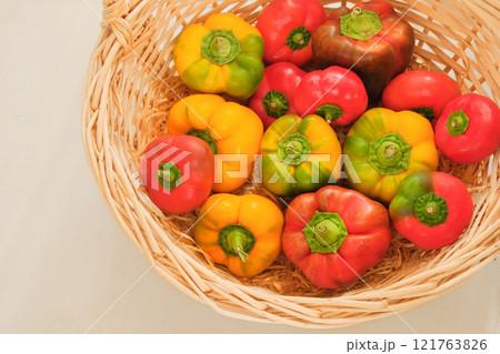 Peppers in a straw basket. Orange and red ripe vegetables. Top view. Place for text. Peppers in a straw basket. Orange and red ripe vegetables. Top view. Place for text. 121763826