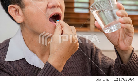 Elderly Man Taking Medicine with a Glass of Water in a Cozy Home Setting for Health and Wellness Concept Elderly Man Taking Medicine with a Glass of Water in a Cozy Home Setting for Health and Wellness Concept 121763964