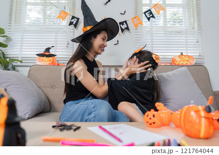 Mother and Daughter Enjoying Halloween Activities Together at Home with Costumes and Decorations 121764044