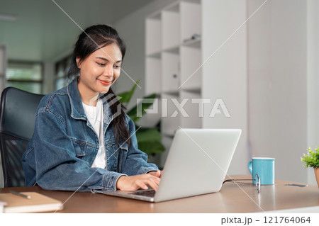 Young Woman Studying Online at Home with Laptop, Focused and Engaged in Learning, Remote Education Concept 121764064