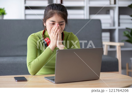 Young Woman Relaxing Happily in Modern Living Room with Laptop and Headphones, Enjoying Leisure Time at Home 121764206