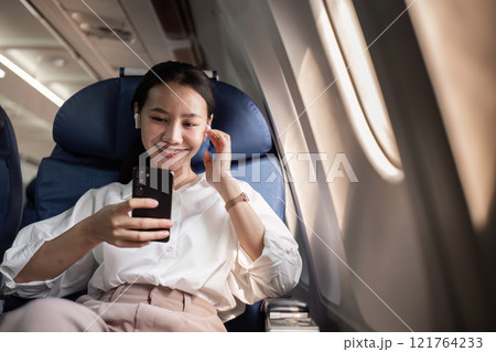 Confident Businesswoman Enjoying In-Flight Entertainment on a Plane Journey for Work and Leisure 121764233
