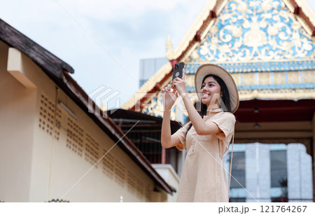 Young Female Tourist Exploring a Cultural Landmark with Mobile Phone in Hand, Capturing Memories and Enjoying the Adventure 121764267
