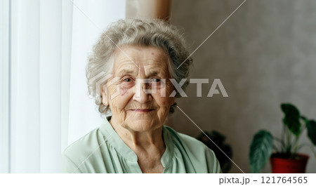 Elderly caucasian woman smiling by window in a peaceful home setting 121764565