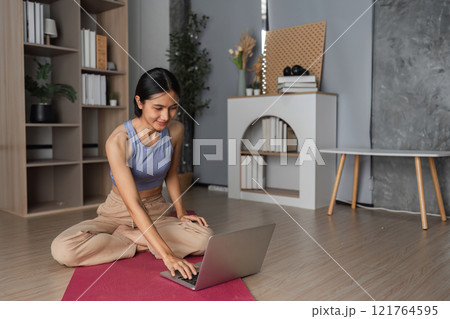 Young Healthy Woman Practicing Yoga at Home in a Modern Living Room Setting for Relaxation and Wellness 121764595