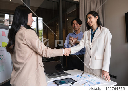 Successful business negotiation, handshake of two businessmen shaking hands with partners celebrating the successful completion of a deal in office conference room. 121764756
