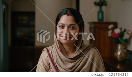 Smiling south asian woman in traditional attire indoors 121764812
