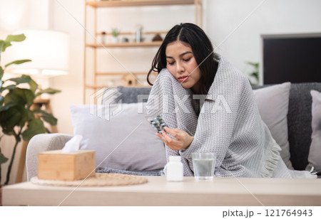 Unwell young woman at home lifestyle indoor comforting space reflecting on health 121764943