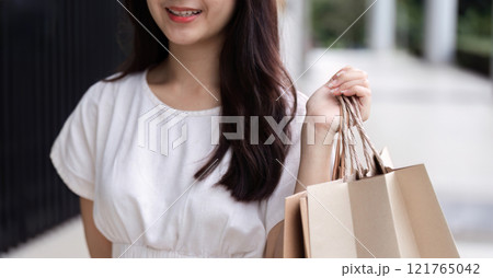 Young Woman Shopping for Black Friday Deals with Bags Full of Purchases in Urban Setting 121765042