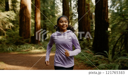 Young asian female jogging in forested park promoting active lifestyle 121765383